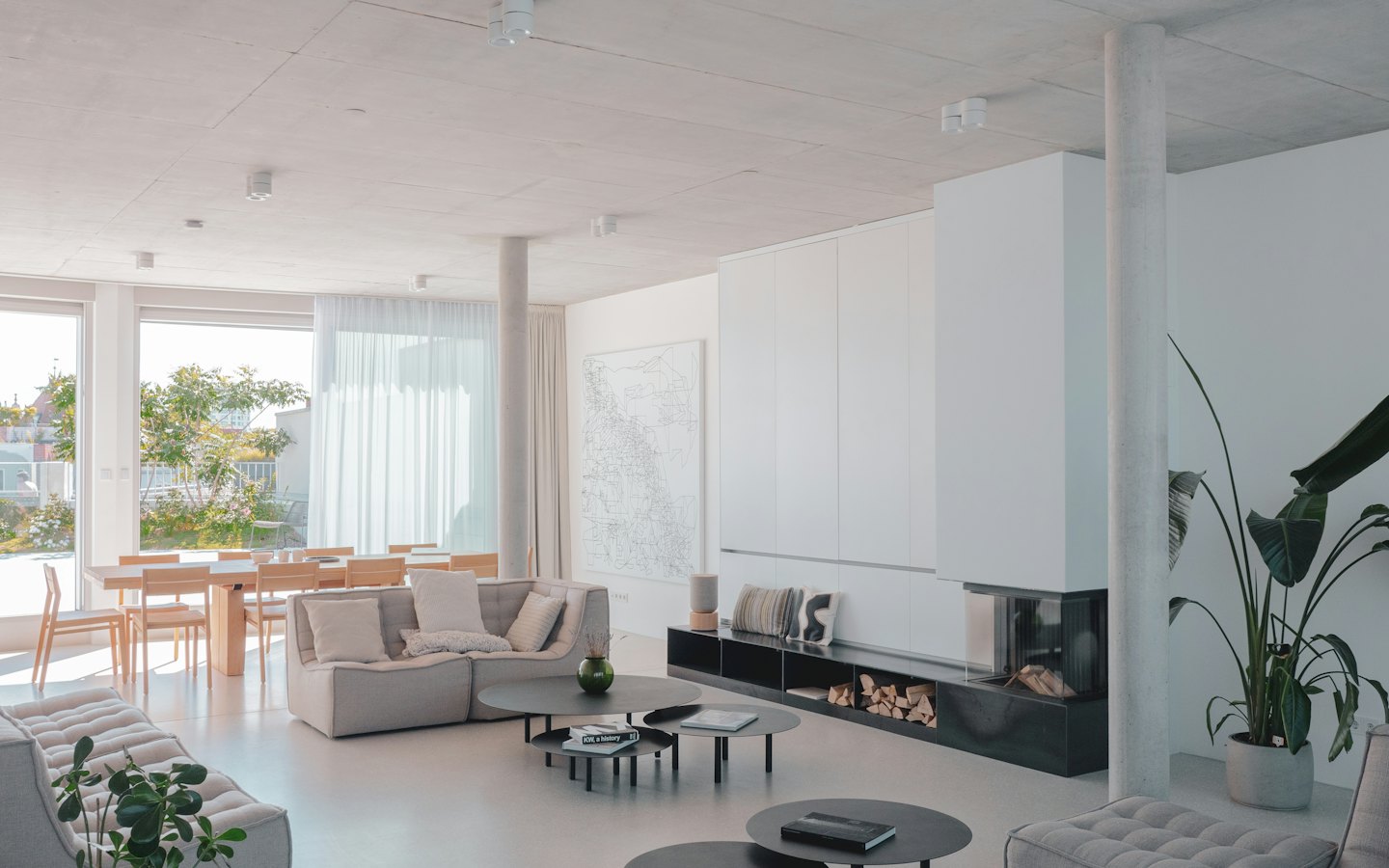 Modern living and dining area with sofas, dining table, and fireplace.